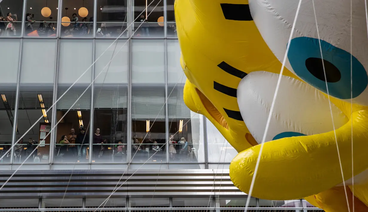 Orang-orang mennonton dari gedung kantor ketika balon Spongebob Squarepants memeriahkan parade perayaan Hari Thanksgiving di kawasan Sixth Avenue, New York, Kamis (28/11/2019). Parade yang membelah jalanan kota New York ini selalu ditunggu setiap tahunnya. (AP Photo/Jeenah Moon)