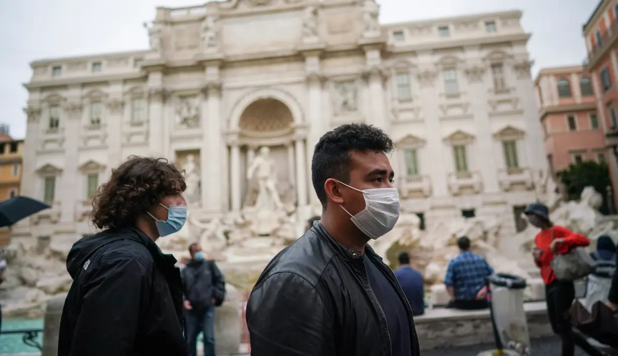 Orang-orang memakai masker saat mereka berjalan melewati Air Mancur Trevi, di Roma pada Sabtu (3/10/2020). Masker wajah harus dipakai setiap saat di luar rumah di ibu kota Italia Roma dan wilayah sekitar Lazio mulai Sabtu, 3 Oktober. (AP Photo/Andrew Medichini)