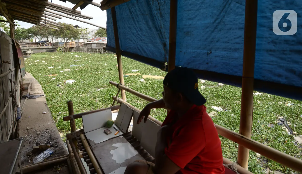 Warga duduk di pinggir kali Prancis di Dadap, Tangerang, Banten, Selasa (23/11/2021). Kali yang dipenuhi sampah dan eceng gondok (Eichhornia crassipes) menimbulkan bau tidak sedap bagi masyarakat sekitar dan membuat aliran menjadi terhambat. (merdeka.com/Imam Buhori)