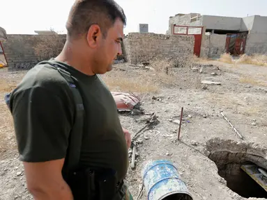 Seorang anggota pasukan Peshmerga bersenjata berjaga di terowongan tempat persembunyian militan ISIS selama operasi penyerangan di Mosul, Irak (19/10). Penemuan terowongan milik militan ISIS itu terdapat di dalam bangunan. (REUTERS/Thaier Al-Sudani)