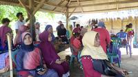 Orang-orang menunggu di tempat penampungan sementara setelah gempa bumi di Adonara, Indonesia, Selasa (14/12/2021). Peringatan dini tsunami ini dicabut usai BMKG mengamati tidak ada gempa susulan dalam 2 jam terakhir. (AP Photo)