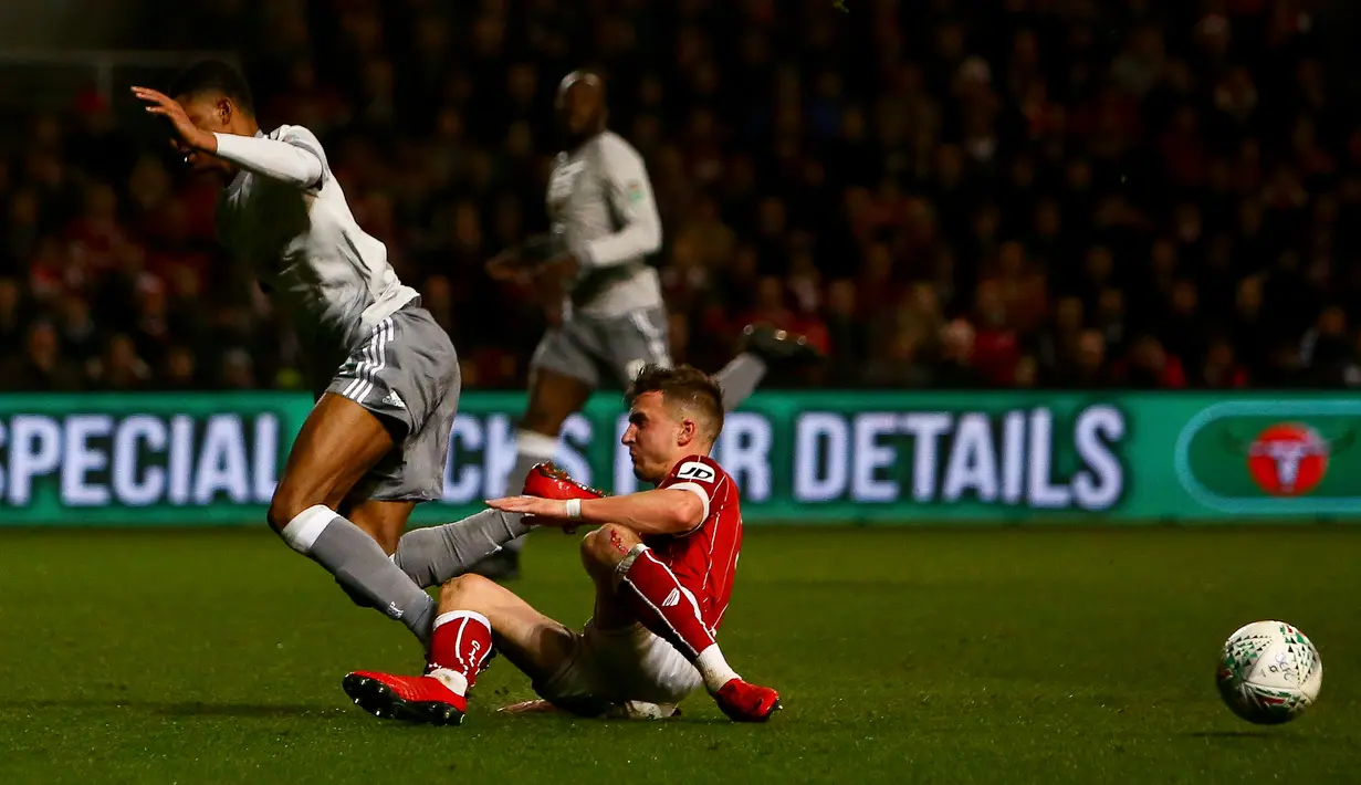 Striker Manchester United, Marcus Rashford merebut bola dari gelandang Bristol City, Jamie Paterson pada perempat final Piala Liga Inggris di Ashton Gate, Kamis (21/12). MU gagal melangkah ke babak empat besar setelah kalah 1-2. (Geoff CADDICK / AFP)