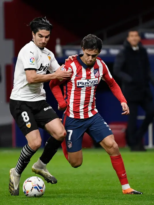 Gelandang Atletico Madrid Joao Felix (kanan) dan gelandang Valencia, Carlos Soler berebut bola pada jornada ke-20 Liga Spanyol di Wanda Metropolitano, Senin (25/1/2021) dini hari WIB. Atletico Madrid memetik kemenangan 3-1 atas Valencia. (PIERRE-PHILIPPE MARCOU/AFP)