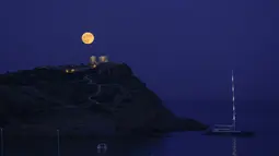 Bulan Purnama Stroberi atau Strawberry Full Moon muncul di belakang Kuil Poseidon marmer kuno di Cape Sounion, sekitar 70 Km selatan kota Athena, Yunani, Kamis (24/6/2021). Strawberry Full Moon adalah istilah yang diambil dari cerita tradisi dari suku-suku asli Amerika (AP Photo/Petros Giannakouris)
