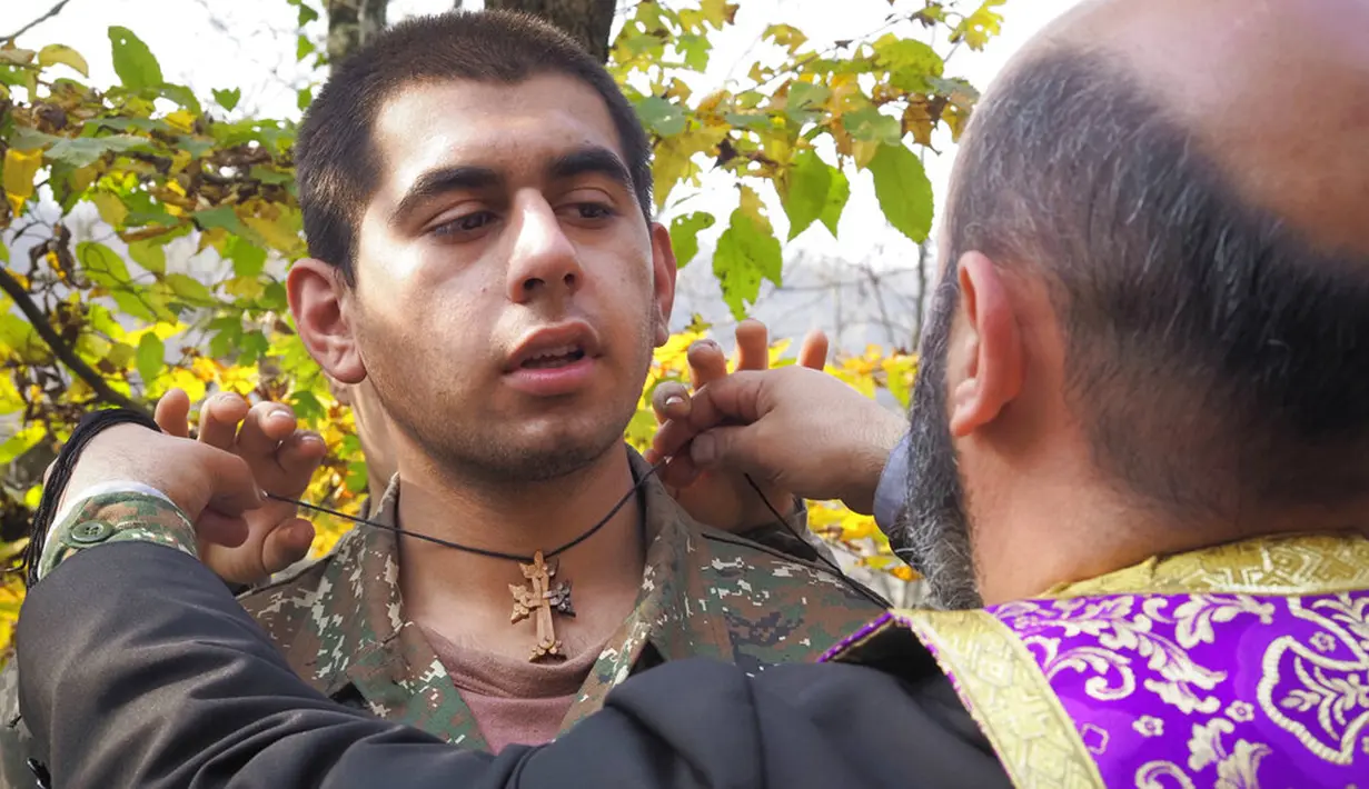 Pendeta Aristakes Hovhannisyan menempatkan salib pada seorang tentara etnis Armenia selama upacara pembaptisan di sebuah kamp militer dekat garis depan konflik di wilayah separatis Nagorno-Karabakh, Azerbaijan, Senin (2/11/2020). (AP Photo)