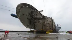 Petugas melintas didepan bangkai kapal Sewol yang berhasil diangkat di pulau barat daya Jindo, Korea Selatan (26/3). Kapal ini sebelumnya tenggelam hampir tiga tahun di kedalaman 44 meter. (HANDOUT / SOUTH KOREAN MARITIME MINISTRY / AFP)