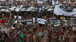 Ratusan orang dari suku asli Brasil menggelar aksi di luar gedung Kongres Nasional di Brasilia, Brasil (25/4). Mereka mengenakan pakaian tradisional dan membawa replika peti mati saat menggelar aksinya. (AP Photo/Eraldo Peres)