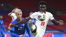 Pemain Inggris, Bukayo Saka, berebut bola dengan pemain Islandia, Albert Gudmundsson, pada laga UEFA Nations League di Stadion Wembley, Kamis (19/11/2020). Inggris menang dengan skor 4-0. (Michael Regan/Pool via AP)