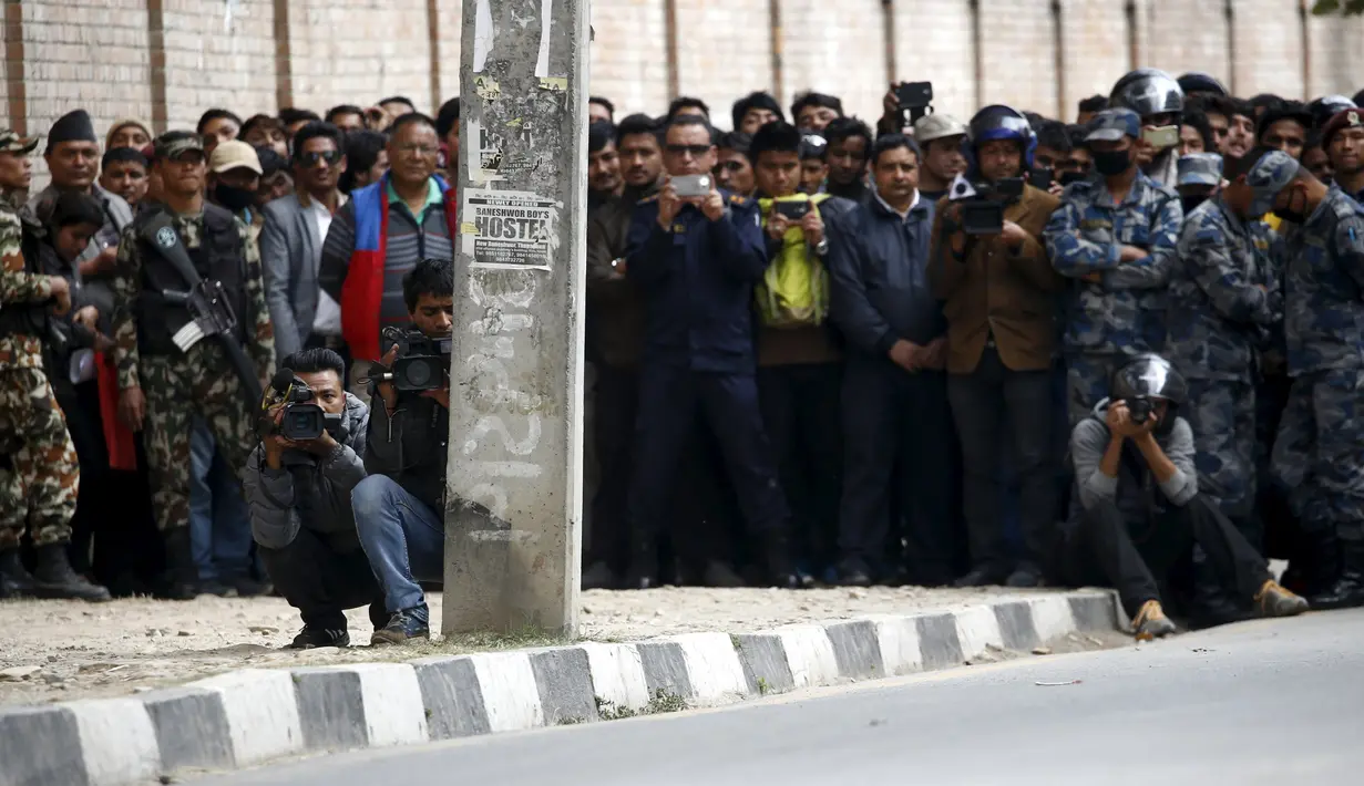 Warga dijaga oleh petugas saat melihat proses pengamanan benda mencurigakan dipinggir jalan kompleks kantor Singha Durbar, Nepal, (1/3). Daerah tersebut dekat dengan rumah kantor Perdana Menteri dan departemen lain. (REUTERS / Navesh Chitrakar)