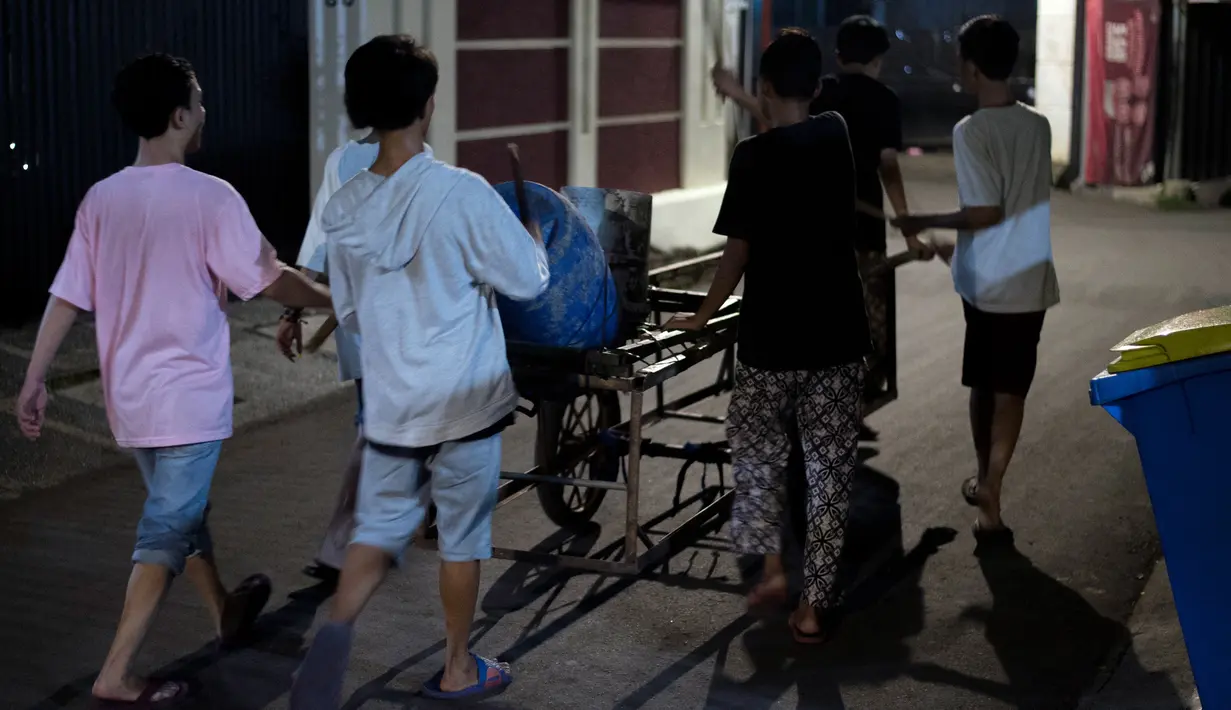 Foto yang diambil pada 19 Mei 2018, para pemuda bernyanyi dan memukul drum berkeliling sekitar lingkungan mereka di Jakarta. Kegiatan tersebut merupakan tradisi selama bulan ramadan membangunkan warga untuk sahur. (AFP PHOTO/BAY ISMOYO)