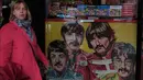 Seorang wanita berjalan melewati gambar The Beatles yang terbuat dari permen  di Liverpool, Inggris, (2/3). Liverpool  tiap tahunnya menadapat 105 juta dollar dari para penggemar The beatles dari seluruh dunia yang hadir ke kota ini. (REUTERS/Phil Noble)