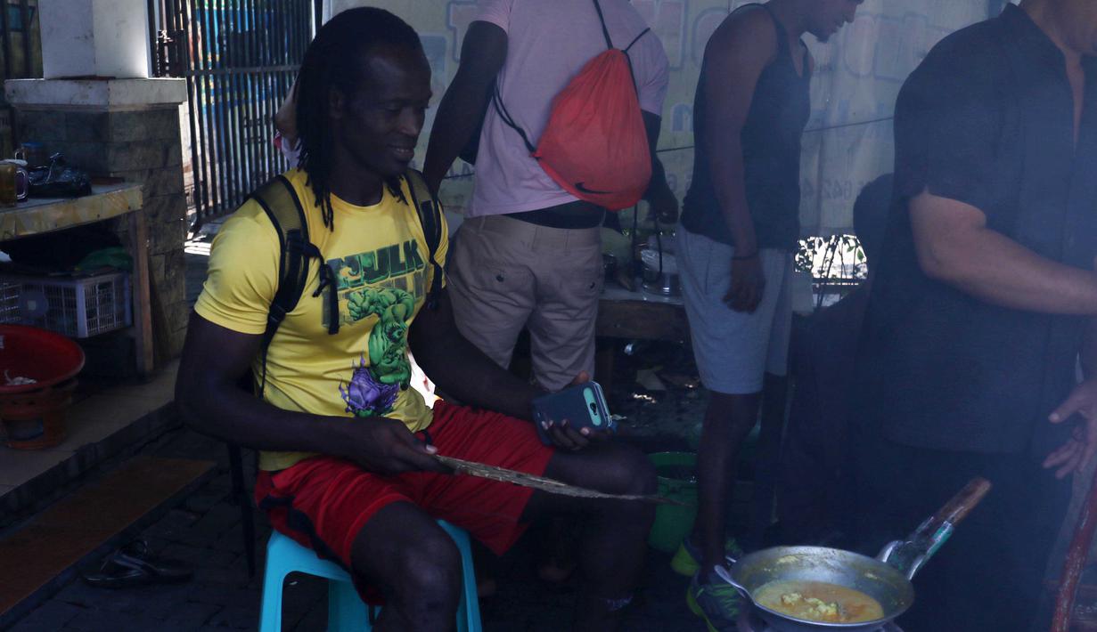 Bek impor Semen Padang, Mahamadou El Hadji tidak ketinggalan mengipas tonseng kambing yang sedang dimasak di Solo, Minggu (13/12/2015). (Nicklas Hanoatubun)
