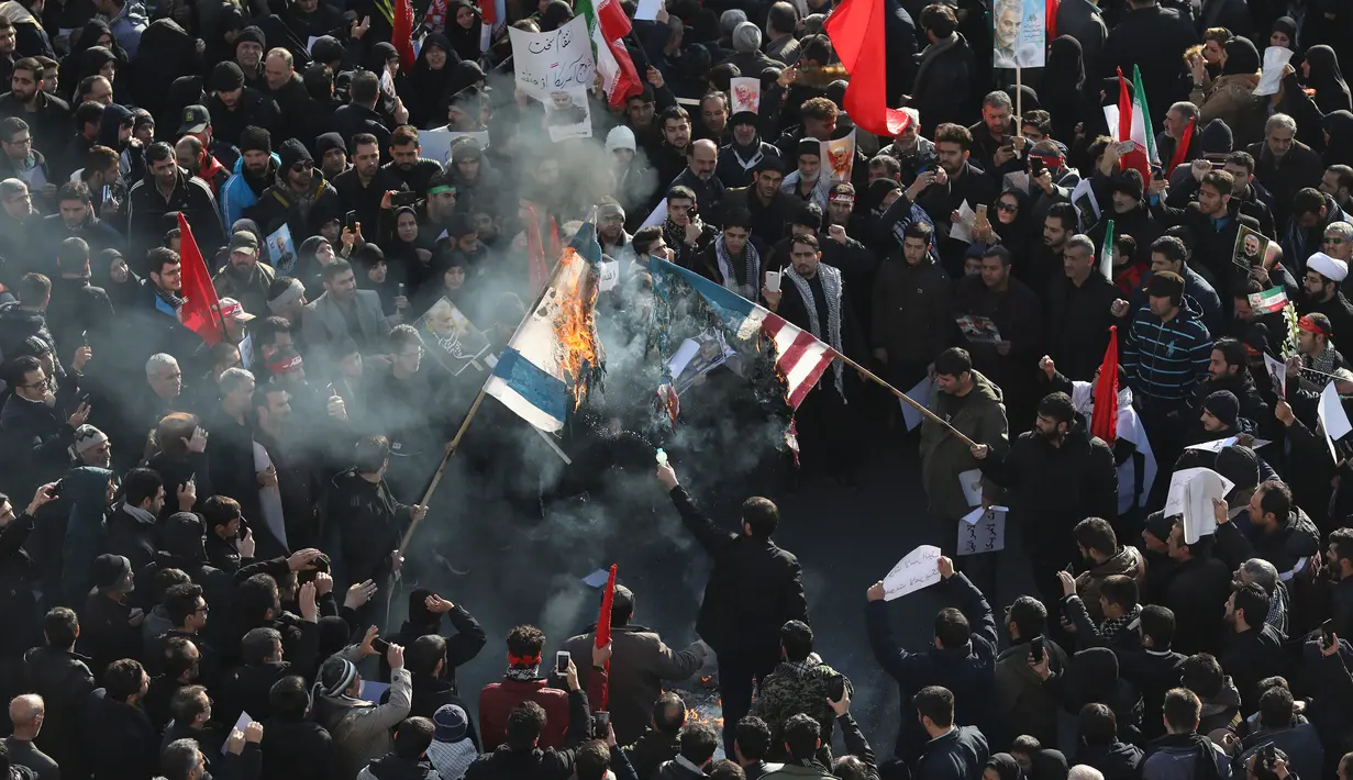Pelayat membakar bendera Amerika Serikat dan Israel saat prosesi pemakaman Jenderal Qasem Soleimani dan sejumlah orang yang tewas dalam serangan Amerika Serikat di Teheran, Iran, Senin (6/1/2020). Pelayat meneriakkan slogan berbunyi 'Matilah Amerika' dan 'Matilah Israel'. (AP Photo/Ebrahim Noroozi)