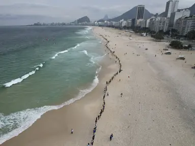 Orang-orang membuat garis di sepanjang pantai Copacabana pada Hari Laut Sedunia di Rio de Janeiro, Brasil, Rabu (8/9/2022). Organisasi Route Brasil menyerukan agar orang-orang berkumpul untuk acara yang diberi nama "Pelukan Itu," dan untuk memungut sampah di pantai, untuk menarik perhatian pada pencemaran laut. (AP Photo/Silvia Izquierdo)