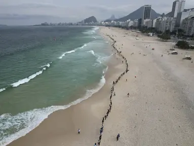 Orang-orang membuat garis di sepanjang pantai Copacabana pada Hari Laut Sedunia di Rio de Janeiro, Brasil, Rabu (8/9/2022). Organisasi Route Brasil menyerukan agar orang-orang berkumpul untuk acara yang diberi nama "Pelukan Itu," dan untuk memungut sampah di pantai, untuk menarik perhatian pada pencemaran laut. (AP Photo/Silvia Izquierdo)