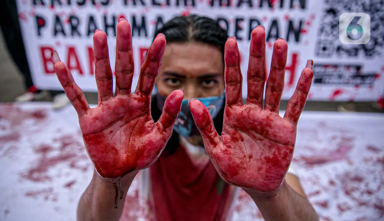 Aktivis melakukan teatrikal dengan menyiramkan darah di tubuhnya saat aksi serentak desak Presiden Jokowi deklarasikan Darurat Iklim di kawasan Patung Kuda, Jakarta, Jumat (19/3/2021). Aksi ini sebagai simbol banyaknya bencana yang terjadi di Indonesia. (Liputan6.com/Faizal Fanani)