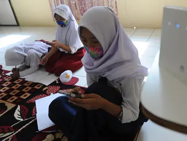 Murid-murid SD dan SMP belajar dengan memanfaatkan wifi gratis di Balai RW kawasan Tegal Gundil, Bogor, Jawa Barat, Senin (21/9/2020). Pemkot Bogor menyebar lebih dari 50 titik wifi publik gratis untuk menunjang Pembelajaran Jarak Jauh (PJJ) siswa di Kota Bogor. (merdeka.com/Arie Basuki)