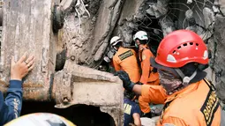 Petugas Basarnas mencari korban di reruntuhan bangunan yang rusak di Mamuju, Sulawesi Barat, Sabtu (16/1/2021). Jalan dan jembatan yang rusak, pemadaman listrik, dan kurangnya alat berat menghambat evakuasi setelah gempa bermagnitudo 6,2 SR yang melanda Majene- Mamuju. (AP Photo/ Sadly Ashari Said)