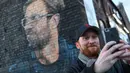 Seorang pria berswafoto dengan mural pelatih klub Liverpool, Jurgen Klopp di Baltic Triangle, Liverpool, Senin (10/12). Banyak yang menyambut pembuatan mural itu namun tidak sedikit pula yang mencibir, termasuk suporter klub Everton. (Paul ELLIS / AFP)