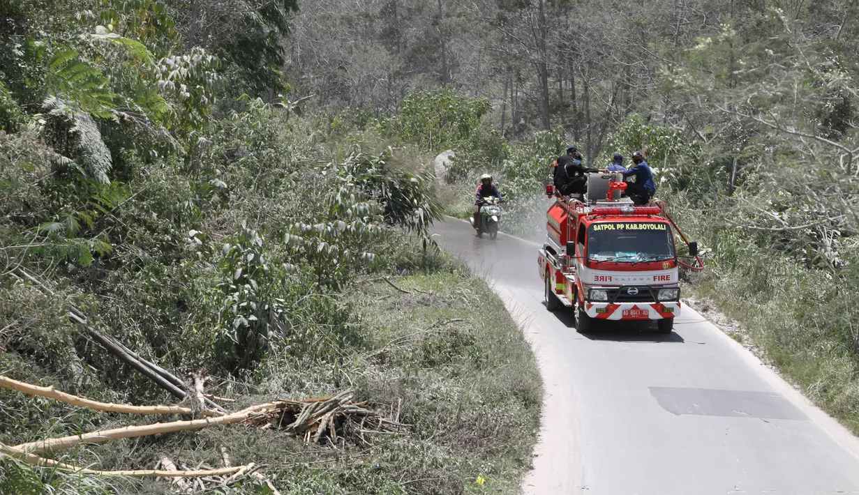 Petugas pemadam kebakaran membersihkan jalan sekolah dari abu pasca erupsi Gunung Merapi di Boyolali, Jawa Tengah pada 13 Maret 2023. Di Desa Klakah Boyolali dampak awan panas guguran Gunung Merapi menyebabkan hujan abu vulkanik dengan ketebalan mencapai 3 cm. (AFP/Dika)