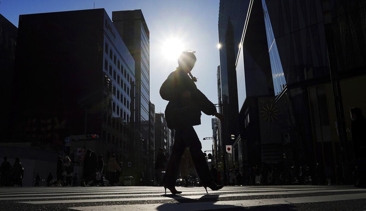 Seorang wanita yang memakai masker untuk membantu mengekang penyebaran COVID-19 menyeberangi jalan di Tokyo, Jepang, 29 Desember 2021. Kenaikan kasus COVID-19 di Jepang sudah mulai lagi dan pemerintah diminta mengantisipasi jumlah tempat tidur. (AP Photo/Eugene Hoshiko)