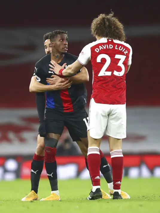 Pemain Crystal Palace Wilfried Zaha (kiri) beselisih dengan pemain Arsenal David Luiz pada pertandingan Liga Inggris di Emirates Stadium, London, Inggris, Kamis (14/1/2021). Pertandingan berakhir imbang 0-0. (Julian Finney/Pool via AP)