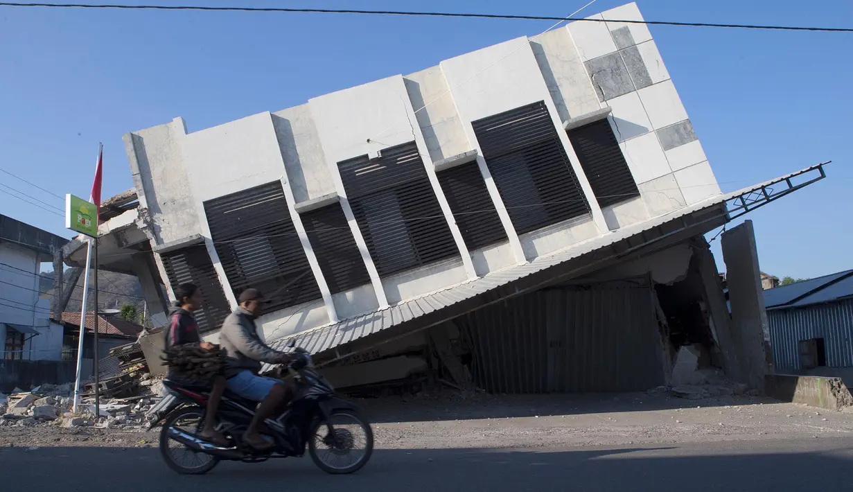 Pengendara melintas di dekat bangunan yang runtuh akibat gempa bumi di Reo, Provinsi Nusa Tenggara Timur, Indonesia, Senin, 17 Agustus 2026. (Foto AP/Firdia Lisnawati)