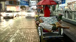 Pengemudi becak tidur siang di luar pusat perbelanjaan di Penang (1/8/2020). Malaysia tengah memperingatkan gelombang kedua virus corona COVID-19. (AFP Photo/Goh Chai Hin)