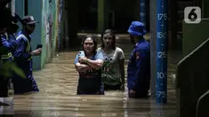 Warga berjalan melintasi banjir di kawasan Kampung Melayu, Jakarta, Senin (8/11/2021). Banjir akibat luapan Kali Ciliwung tersebut merendam pemukiman setinggi 60 cm sejak 7 November 2021 sore. (Liputan6.com/Faizal Fanani)