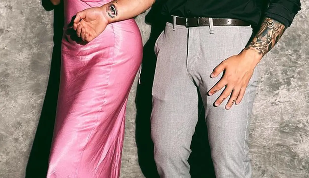 Gaya berani Millen Cyrus dan kekasih. Dengan gaun merah muda bertali spageti, Millen berpose menutupi salah satu payudaranya dengan satu tangannya, sedangkan kekasihnya tampil dengan kemeja hitam dan celana panjang abu-abu. Foto: Instagram.