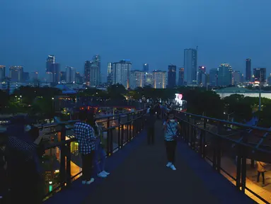 Pengunjung menikmati pemandangan dari Skywalk Senayan Park, Jakarta, Rabu (29/12/2021). Kawasan yang menyajikan pemandangan lanskap perkotaan itu menjadi alternatif destinasi wisata Jakarta yang instagramble dengan spot foto yang beragam. (merdeka.com/Imam Buhori)