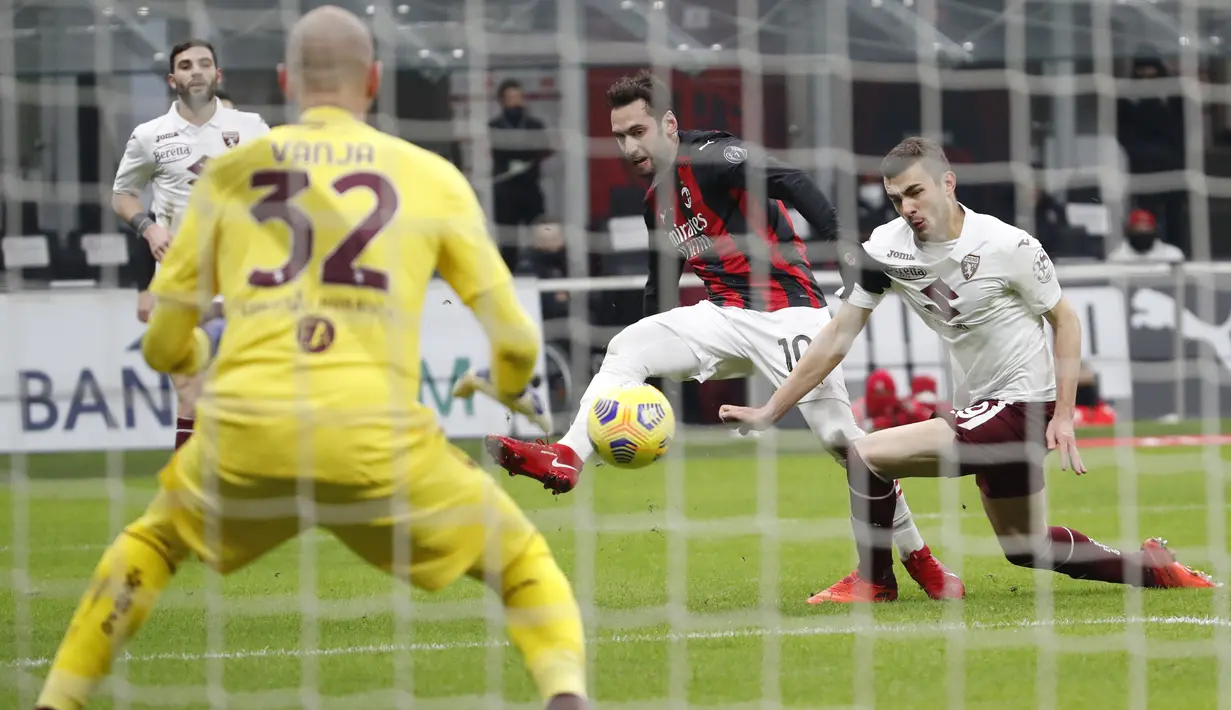 Gelandang AC Milan, Hakan Calhanoglu (tengah) berusaha mencetak gol ke gawang Torino pada babak 16 besar Coppa Italia 2020/2021 di San Siro, Rabu (13/1/2021) dini hari WIB. Laga terkunci 0-0, AC Milan menang 5-4 atas Torino di babak adu penalti. (AP Photo/Antonio Calanni)
