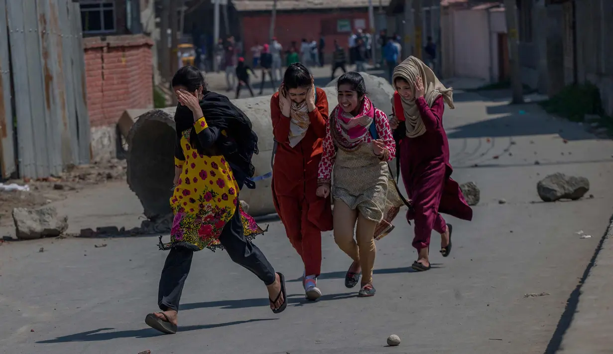 Gadis-gadis Kashmir berlari selama bentrokan di Srinagar, Kashmir yang dikuasai India, (1/4). Pengunjuk rasa memprotes menyusul tewasnya delapan pemberontak dalam bentrokan dengan pasukan pemerintah. (AP Photo / Dar Yasin)
