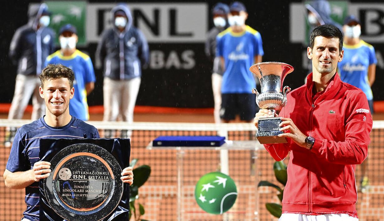 Petenis Serbia, Novak Djokovic, mengangkat trofi bersama Diego Schwartzman usai menjuarai Italia Terbuka di Roma, Senin (21/9/2020). Djokovic mengalahkan petenis Argentina, Diego Schwartzman, dengan skor 7-5 dan 6-3. (Alfredo Falcone/LaPresse via AP)