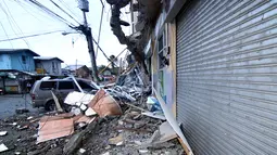 Sebuah mobil yang terparkir terjebak di bawah puing-puing bangunan yang runtuh akibat gempa 6,5 SR yang melanda Surigao City, Pulau Mindanao, Filipina (11/2). (AFP/Erwin Mascarinas)