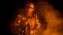 Seorang pekerja mengenakan pakaian pelindung saat berada di tungku untuk membuat baja di Salzgitter, Jerman (22/3). Karena pantulan api, baju pelindung pekerja jadi terlihat berwarna keemasan. (AP Photo / Markus Schreiber)