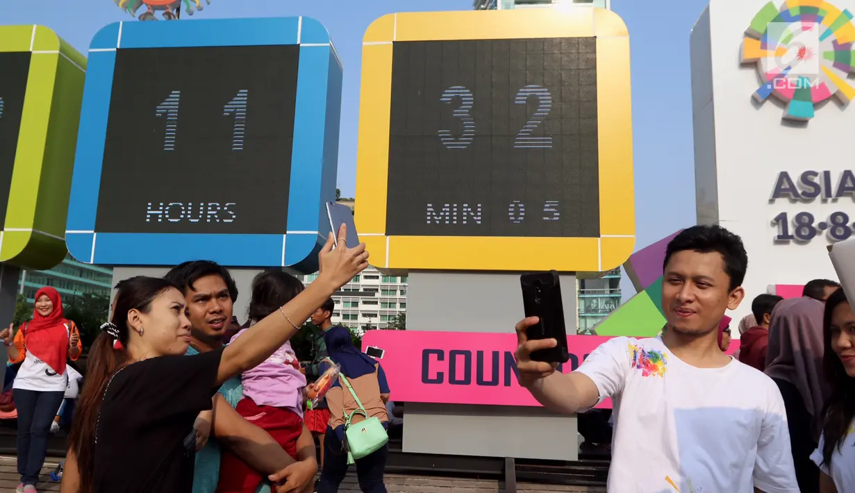 Warga swafoto dan selfie dengan latar layar Countdown Asian Games 2018 saat Car Free Day di Bundaran HI, Jakarta, Minggu, (10/09). Hitung mundur pelaksanaan Asian Games 2018 kini telah memasuki H - 342. (Liputan6.com/Fery Pradolo)
