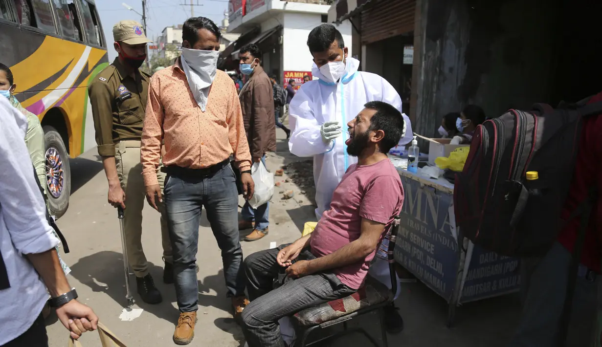 Seorang petugas kesehatan mengumpulkan sampel seorang penumpang untuk diuji COVID-19 di sebuah terminal bus di Jammu, India (26/3/2021). Pemerintah India telah mengumumkan rencana untuk menyuntik 300 juta orang pada Agustus. (AP Photo/Channi Anand)