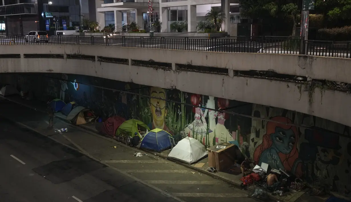 Tunawisma tinggal di tenda-tenda di trotoar di bawah jalan layang di sepanjang Paulista Avenue Sao Paulo, Brasil pada Rabu malam, 26 Januari 2022. Sensus baru menunjukkan populasi tunawisma di Sao Paulo telah meningkat 30% selama pandemi COVID-19. (AP Photo/Andre Penner)