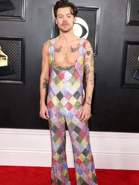 Harry Styles memilih jumpsuit low-neck bertabur kristal swarovski dari Gucci yang memperlihatkan tatonya.  [@stealthelook].