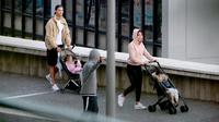 Cristiano Ronaldo bersama Georgina Rodriguez mendorong dua kereta bayi saat mereka berjalan-jalan dengan anak-anak mereka di Funchal pada 28 Maret 2020. Pesepakbola Cristiano Ronaldo dan kekasihnya, Georgina Rodriguez membagikan kabar duka. (AFP/HELDER SANTOS)
