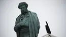 Seorang pria memberi isyarat saat dia memanjat dekorasi Tahun Baru di sebelah patung Alexander Pushkin selama protes terhadap pemenjaraan pemimpin oposisi Alexei Navalny di Moskow, Rusia, Sabtu (23/1/2021). (AP Photo/Pavel Golovkin)