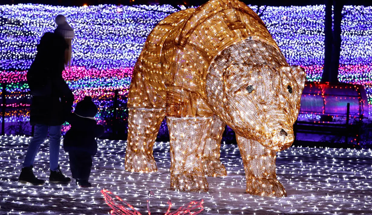 Seorang wanita bersama anaknya bermain diantara cahaya lampu yang memenuhi sebuah taman di Minsk, Belarus (5/2). Setelah matahari terbenam empat puluh pameran seni instalasi lampu menghiasi seluruh taman di Belarus. (AP Photo/Sergei Grits)