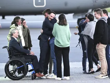 Pekerja bantuan Belgia, Olivier Vandecasteele (kiri tengah) disambut oleh keluarganya di landasan ketika dia turun dari pesawat militer Belgia di bandara militer Melsbroek di Melsbroek, Belgia, Jumat (26/5/2023). (Didier Lebrun/Pool Photo via AP)