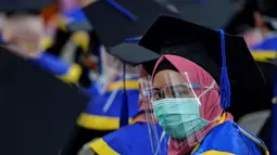 Seorang siswa yang mengenakan masker dan pelindung sebagai tindakan pencegahan terhadap virus Corona COVID-19 mengikuti acara wisuda SMK Farmasi di Banda Aceh (24/9/2020). (AFP/Chaideer Mahyuddin)