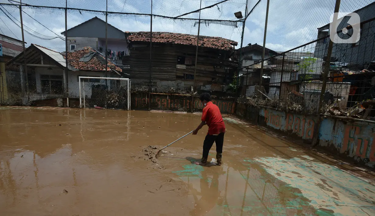 Warga membersihkan lumpur sisa banjir di Kelurahan Rawa Jati, Jakarta, Selasa (9/2/2021). Endapan lumpur yang mengendap akibat luapan Kali Ciliwung. (merdeka.com/Imam Buhori)