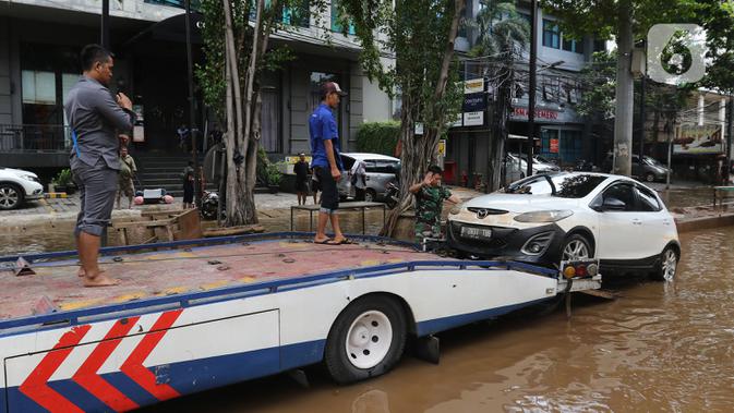 Sebuah mobil dipindahkan setelah terendam banjir di kawasan Kemang, Jakarta, Kamis (2/1/2020). Banjir yang melanda Jakarta dan sekitarnya mengakibatkan banyak kendaraan terendam air. (Liputan6.com/Herman Zakharia)