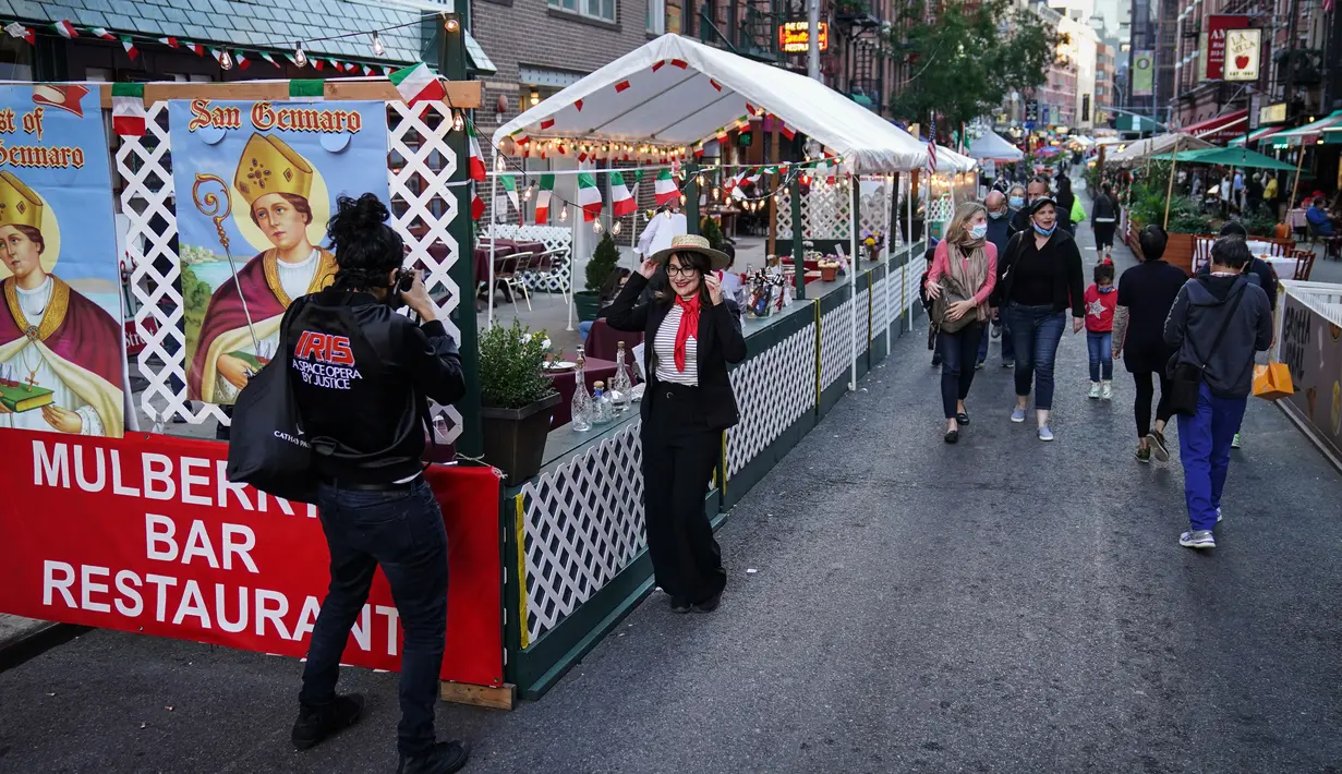 Orang-orang berjalan melalui di mana restoran mengoperasikan area luar ruangan (outdoor) hingga ke trotoar dan jalanan di New York, 3 Oktober 2020. Kota itu mengizinkan restoran membuat area makan outdoor sebagai upaya mengatasi dampak ekonomi COVID-19 yang berkelanjutan. (AP Photo/John Minchillo)