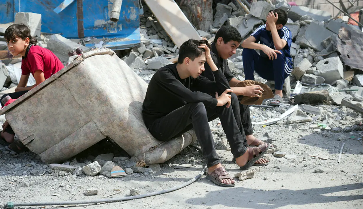 Anak-anak Palestina duduk di reruntuhan bangunan yang hancur akibat serangan udara Israel di Kamp Nuseirat, Jalur Gaza, Senin (16/10/2023). (AP Photo/Hatem Moussa, File)