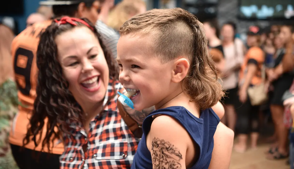 Seorang anak kecil mengikuti Mulletfest 2018 di Kota Kurri Kurri, 150 km utara Sydney, Australia, Sabtu (24/2). Mullet populer sejak tahun 1970-an dan menjadi gaya rambut andalan banyak selebritas dunia. (PETER PARKS/AFP)